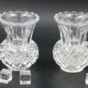 以下が含まれることがあります： ダイヤモンド模様の透明なガラスの花瓶が2つ。花瓶は高さ約10cmで、縁がギザギザになっています。