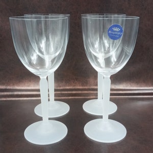 May include: Set of four clear glass wine glasses with frosted stems and bases. The glasses have a BergHOFF logo on the side.