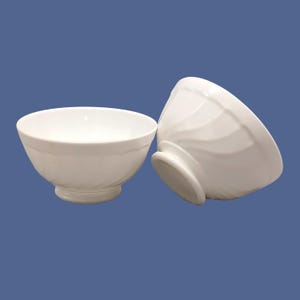 Może przedstawiać: Dwie białe ceramiczne miski z żebrowanym wzorem. Miski są puste i stoją na niebieskim tle.