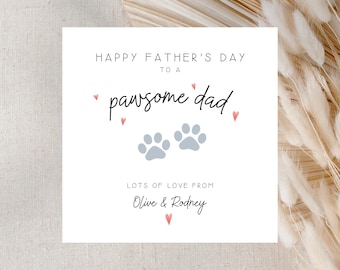May include: A white Father's Day card with the text "Happy Father's Day to a pawsome dad." The card features two light blue paw prints and small pink hearts. The card is signed "Lots of love from Olive & Rodney."