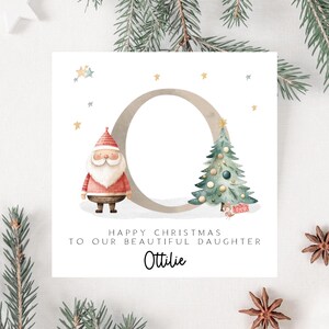 May include: A Christmas card with a watercolor illustration. It features a Santa Claus figure, a decorated Christmas tree, and the text "Happy Christmas to our beautiful daughter Ottilie."