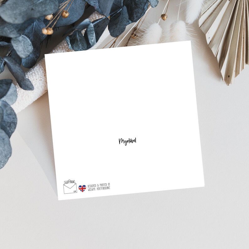 May include: A blank white card with the word "Myriad" written in black ink at the bottom. The card has a small logo in the bottom left corner that says "Letter" with a stylized envelope and a heart.