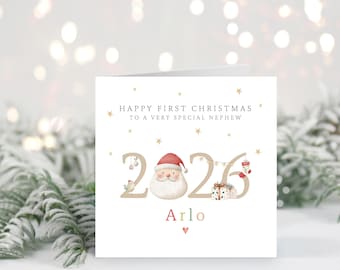 May include: A square greeting card with the text Happy First Christmas To A Very Special Nephew above the year 2026. The number zero is replaced by a Santa Claus face with a red hat. The name Arlo is printed below with a small red heart.