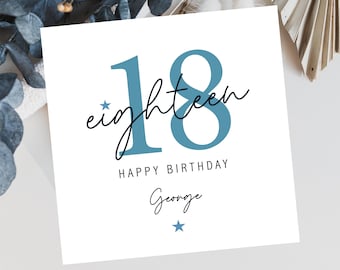 Può includere: Un biglietto bianco con il numero 18 in blu e la parola "eighteen" scritta in corsivo. Il biglietto dice "Happy Birthday George" con una stella blu sotto il nome.