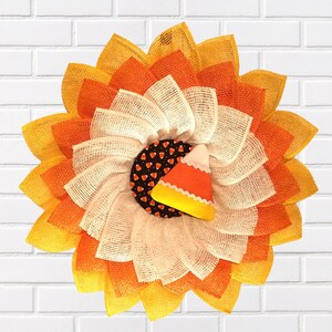 玄関ドアの装飾に最適なキャンディコーンフラワーリース。ドアの間にも収まる薄型。ハロウィンの飾り、新築祝いのギフト、ひまわりの花びら付き。