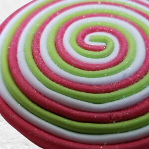 May include: Close-up of a red, white, and green swirl lollipop with a glittery finish.