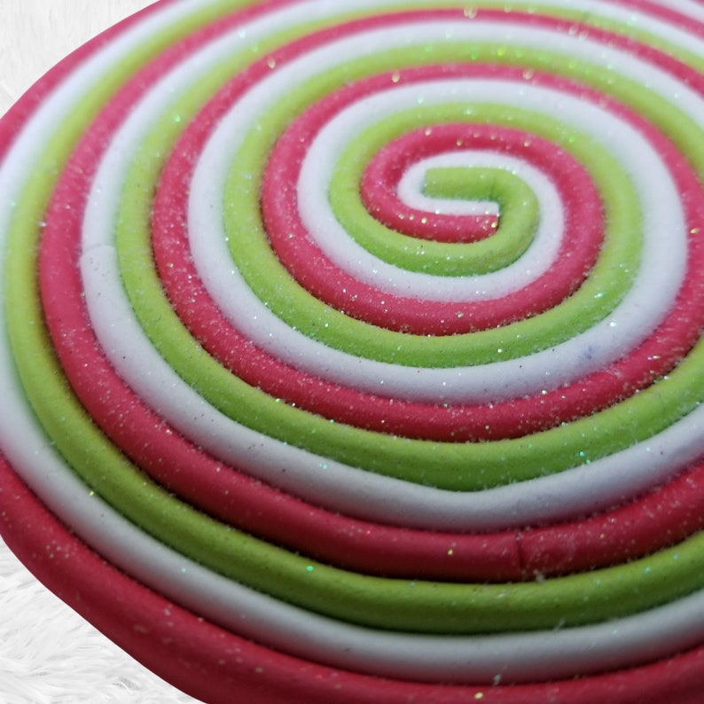 May include: Close-up of a red, white, and green swirl lollipop with a glittery finish.