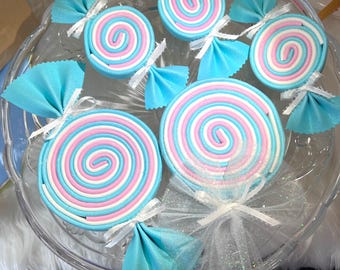 May include: A set of five decorative candy-shaped ornaments. The ornaments are made of fabric and are in the shape of lollipops and wrapped candies. The lollipops are pink, white, and blue, and the candies are blue and white.