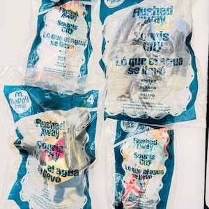May include: Four sealed McDonald's Happy Meal toys from the animated film "Flushed Away." Each toy is in a clear plastic bag with a blue and white border and the McDonald's logo. The text on the bags is in English, Spanish, and French.