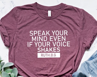 May include: A maroon t-shirt with the text "Speak your mind even if your voice shakes" and "Ruth.B.G." in white lettering.