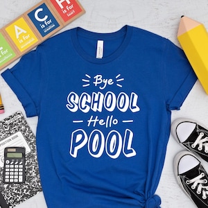 May include: A royal blue t-shirt with the text "Bye School - Hello Pool" in white. The image includes black sneakers, school supplies, and wooden blocks spelling "TEACH".