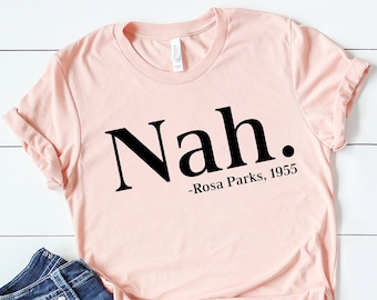 May include: A pink t-shirt with the text "Nah." and the quote "Rosa Parks, 1955" printed in black.