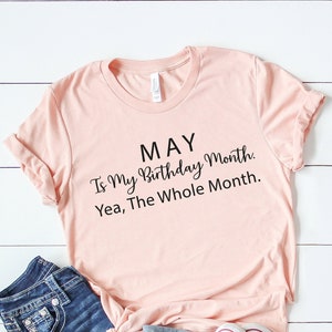 May include: A pink t-shirt with the text "MAY Is My Birthday Month. Yea, The Whole Month." printed in black.