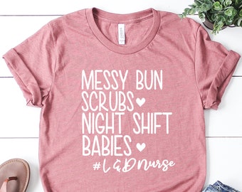 May include: A pink t-shirt with the text "Messy Bun Scrubs Night Shift Babies #L&Dnurse" in white.