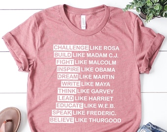 Könnte beinhalten: Ein pinkfarbenes T-Shirt mit weißem Text, der "Challenge like Rosa, Build like Madam C.J., Fight like Malcolm, Inspire like Obama, Dream like Martin, Write like Maya, Think like Garvey, Lead like Harriet, Educate like W.E.B., Speak like Frederic, Believe like Thurgood" lautet.