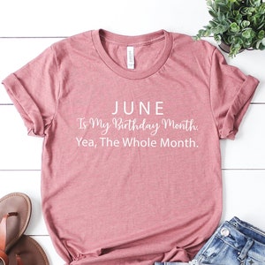 Puede incluir: Una camiseta de color rosa p&aacute;lido con el texto "JUNE Is My Birthday Month. Yea, The Whole Month." impreso en blanco.