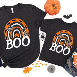 May include: Two black t-shirts with a white rainbow design and the word "BOO" in white. The rainbow has orange and black bats, a pumpkin, and spiderwebs.