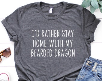 May include: A dark grey t-shirt with the text "I'd rather stay home with my bearded dragon" printed in white.