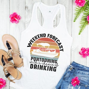 May include: White tank top with a vintage-style graphic that says "Weekend Forecast: Pontooning with a chance of drinking". The graphic features a sunset and a pontoon boat.