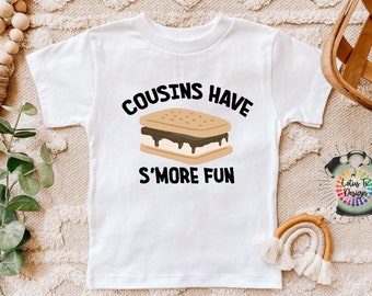 May include: White t-shirt with a black graphic that says "Cousins Have S'more Fun" and a cartoon image of a s'more.