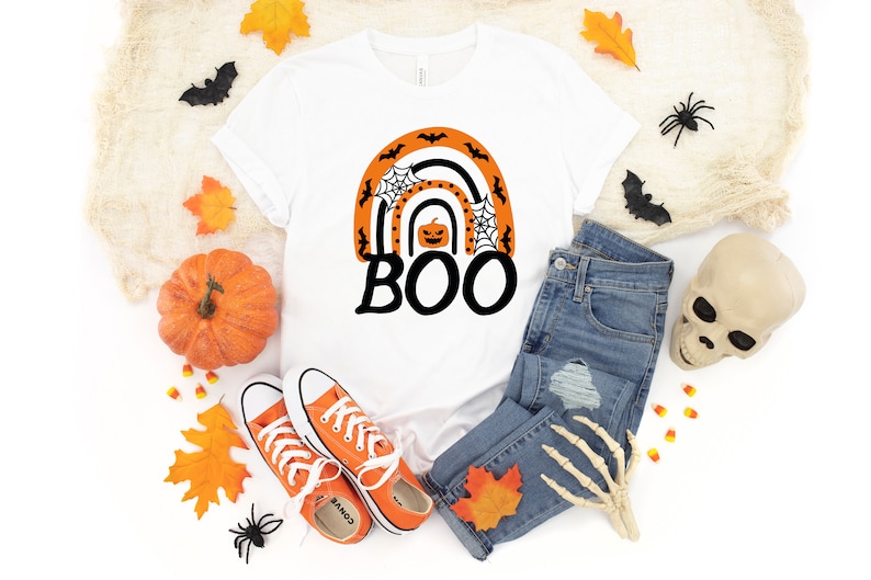 May include: White t-shirt with an orange and black rainbow design featuring a pumpkin and the word "BOO".