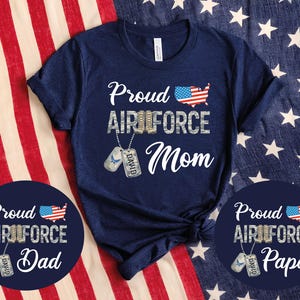 May include: Navy blue t-shirt with the text "Proud Air Force Mom" in white, with a US flag graphic. Includes a dog tag with the name "David". Also includes two navy blue circular graphics with the text "Proud Air Force Dad" and "Proud Air Force Papa".