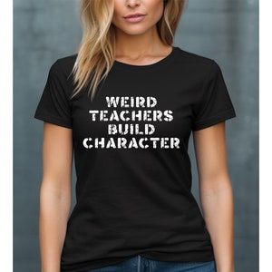 Op de afbeelding: Zwart T-shirt met witte tekst die "Weird Teachers Build Character" zegt.