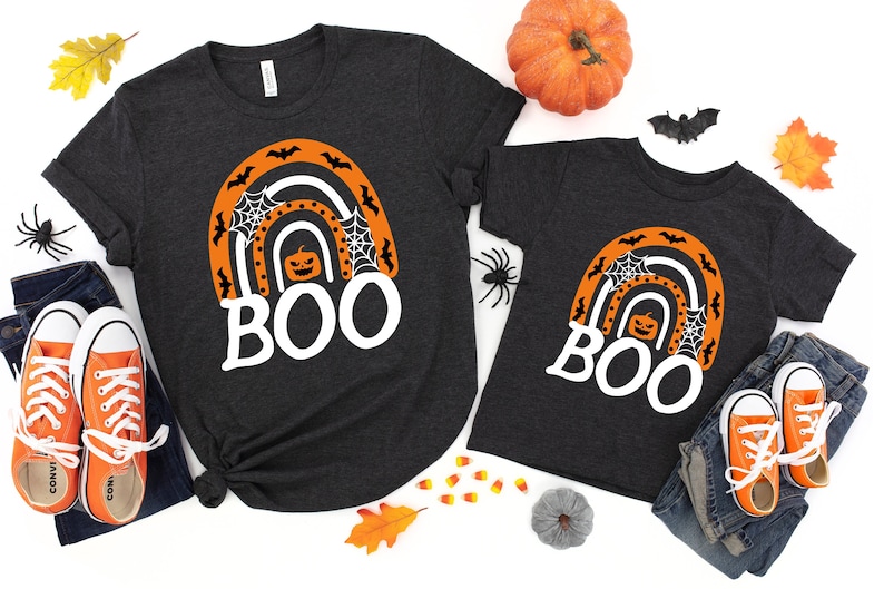 May include: Two black t-shirts with a white rainbow design and the word "BOO" in white. The rainbow has orange and black bats, a pumpkin, and spiderwebs.