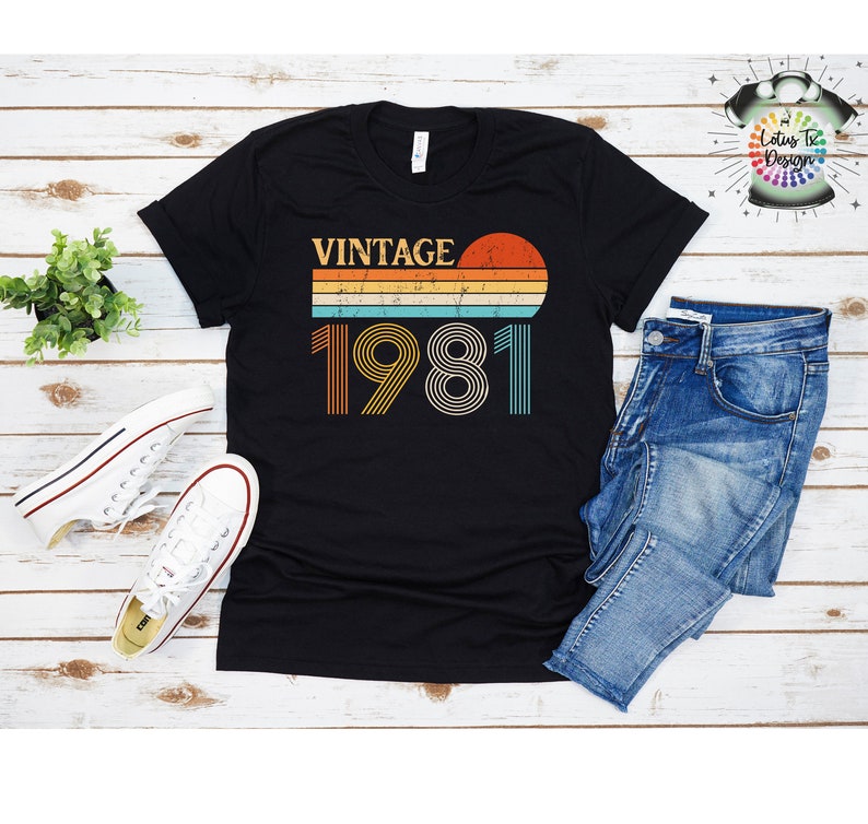 May include: Black t-shirt with a vintage 1981 design featuring a sunset and striped lines in orange, yellow, blue, and white.