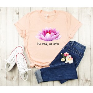 May include: A peach-colored t-shirt with a pink lotus flower graphic and the text "No mud, no lotus".