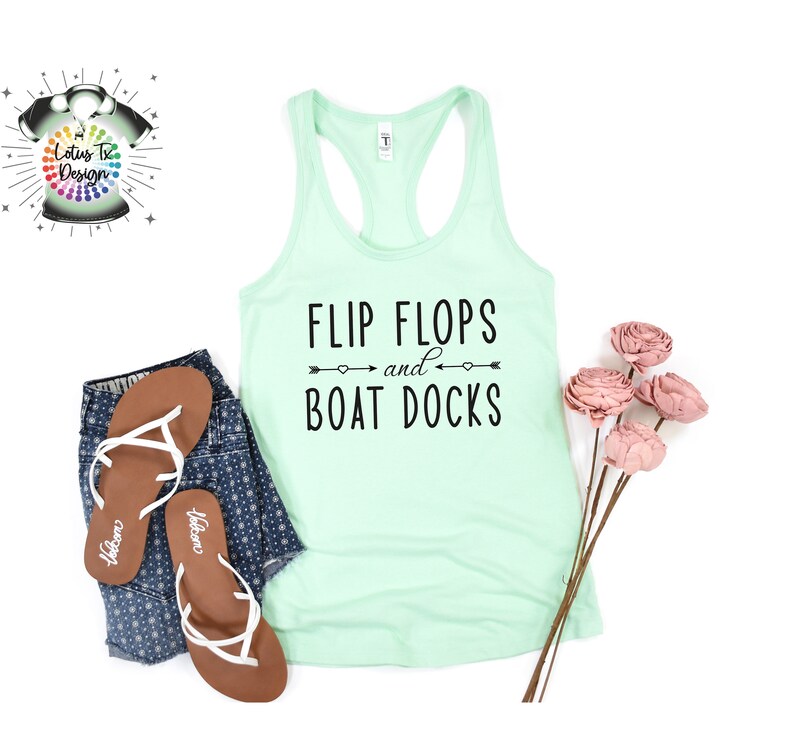 May include: A light green tank top with the text "FLIP FLOPS and BOAT DOCKS" in black. The text is surrounded by two arrows with hearts at the ends.