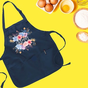 May include: Navy blue apron with a floral design and the word "GRAMMY" in white text. The apron has a large pocket on the front.