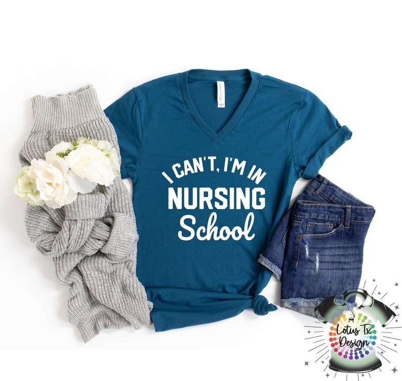 May include: Teal blue v-neck t-shirt with the text "I can't, I'm in Nursing School" in white lettering.