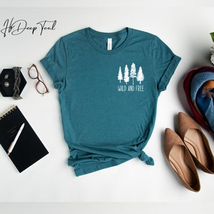May include: Teal blue t-shirt with a white graphic of five trees and the text "Wild and Free".