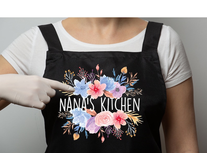 May include: Black apron with adjustable straps featuring a floral design and the text "NANA'S KITCHEN" in white.