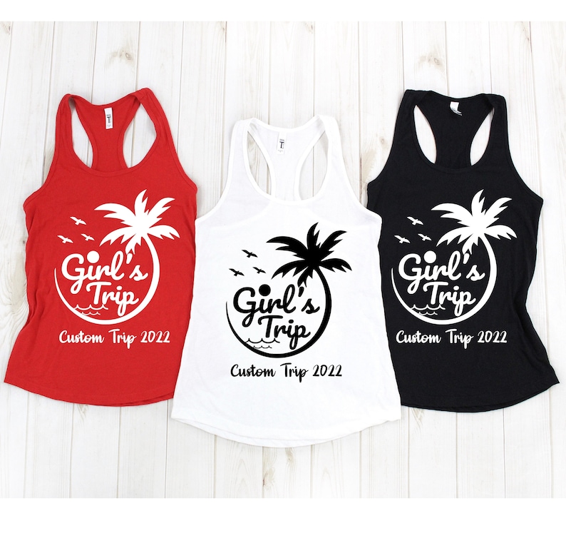 Puede incluir: Tres camisetas sin mangas en rojo, blanco y negro. Cada camiseta presenta un gr&aacute;fico blanco o negro con el texto "Girl's Trip" y "Custom Trip 2022", junto con una palmera y p&aacute;jaros.
