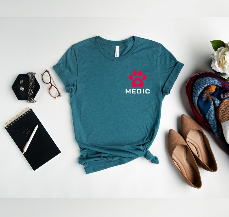 May include: Teal blue t-shirt with a red paw print and the word "MEDIC" in white lettering.