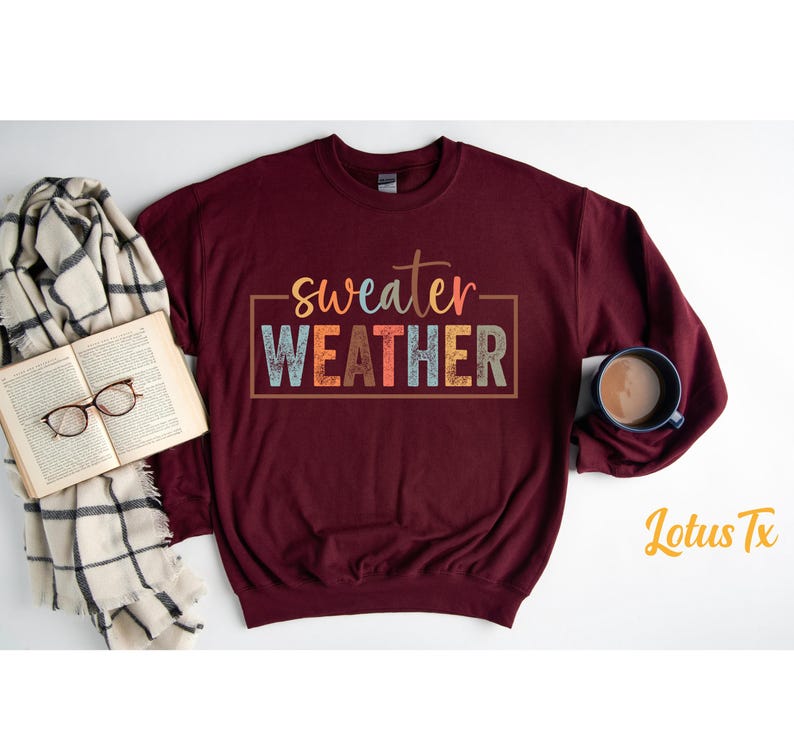 May include: A maroon sweatshirt with the text "sweater weather" in colorful letters. The text is in a box with a white outline.