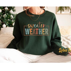 May include: A dark green sweatshirt with the text "sweater weather" in a colorful retro font.