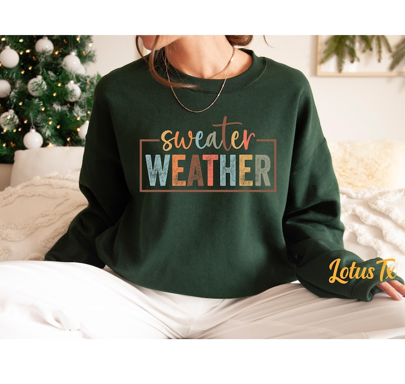 May include: A dark green sweatshirt with the text "sweater weather" in a colorful retro font.