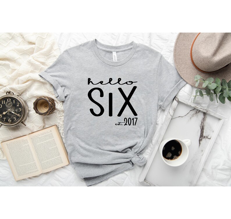 May include: Gray t-shirt with the text "hello six est. 2017" printed in black.