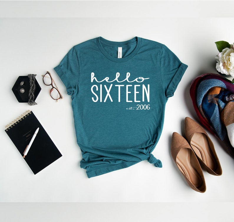 May include: Teal blue t-shirt with white text that reads "hello sixteen est. 2006".