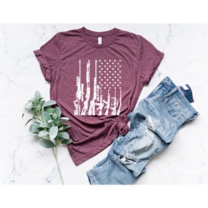May include: A maroon t-shirt with a white graphic of an American flag made up of guns.