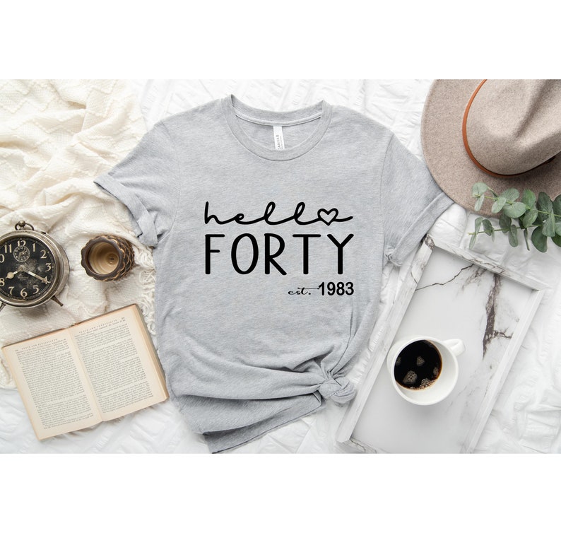 May include: Gray t-shirt with black text that reads "hello forty est. 1983" with a small heart symbol.