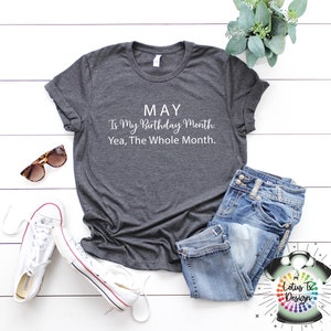 May include: A dark gray t-shirt with white text that reads "MAY Is My Birthday Month. Yea, The Whole Month."