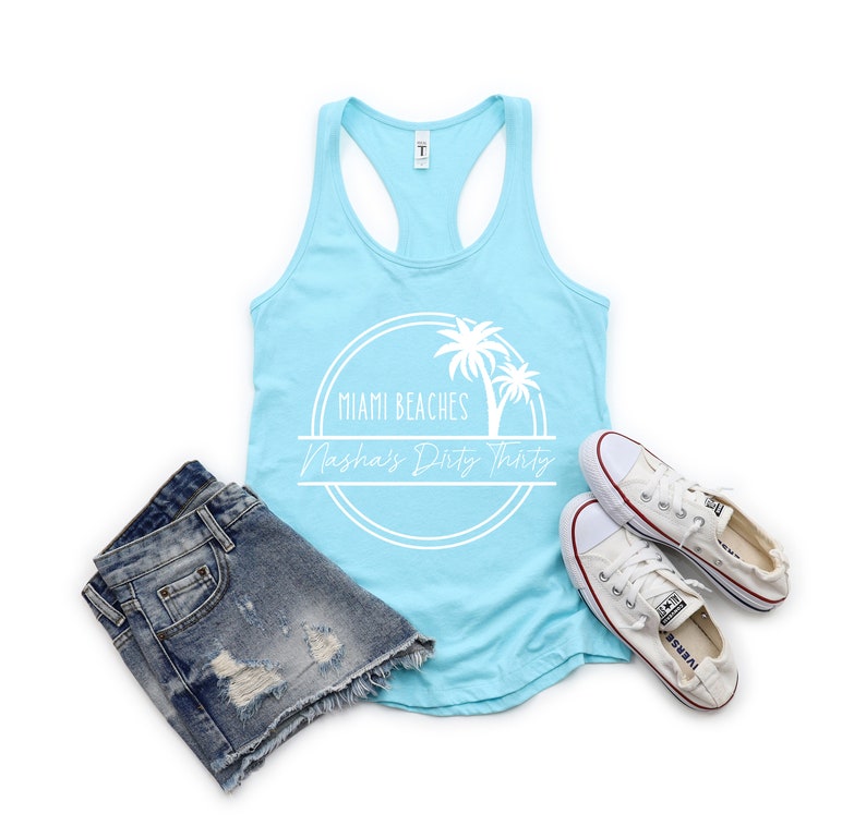 May include: A light blue tank top with a white graphic of palm trees and the text "Miami Beaches Nasha's Dirty Thirty".