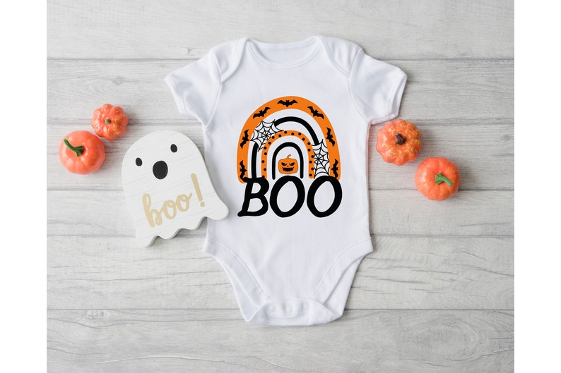 May include: White baby onesie with an orange and black rainbow design featuring a pumpkin, spiderwebs, and bats. The text "BOO!" is written in black below the rainbow.