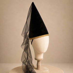 A mannequin head wearing a black hat with a long, flowing veil draped over the side.