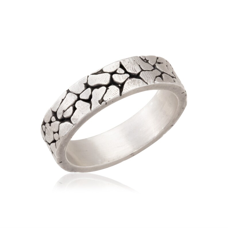 May include: A silver ring with a textured, cracked surface design.