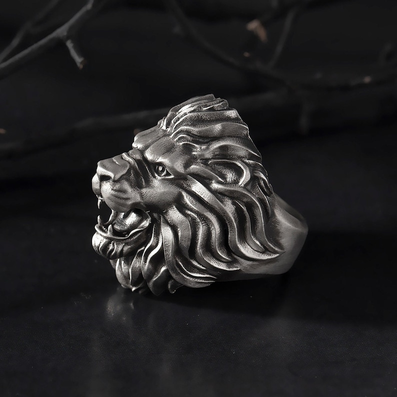Puede incluir: Un anillo de cabeza de le&oacute;n de plata con un dise&ntilde;o detallado. El anillo est&aacute; hecho de metal y tiene un dise&ntilde;o realista de cabeza de le&oacute;n.